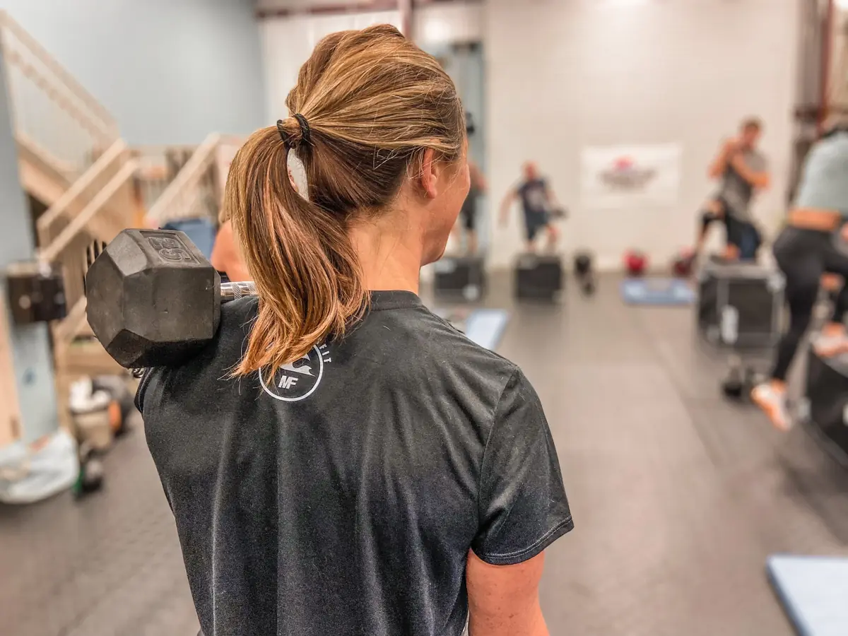 A member with a dumbbell on her shoulder