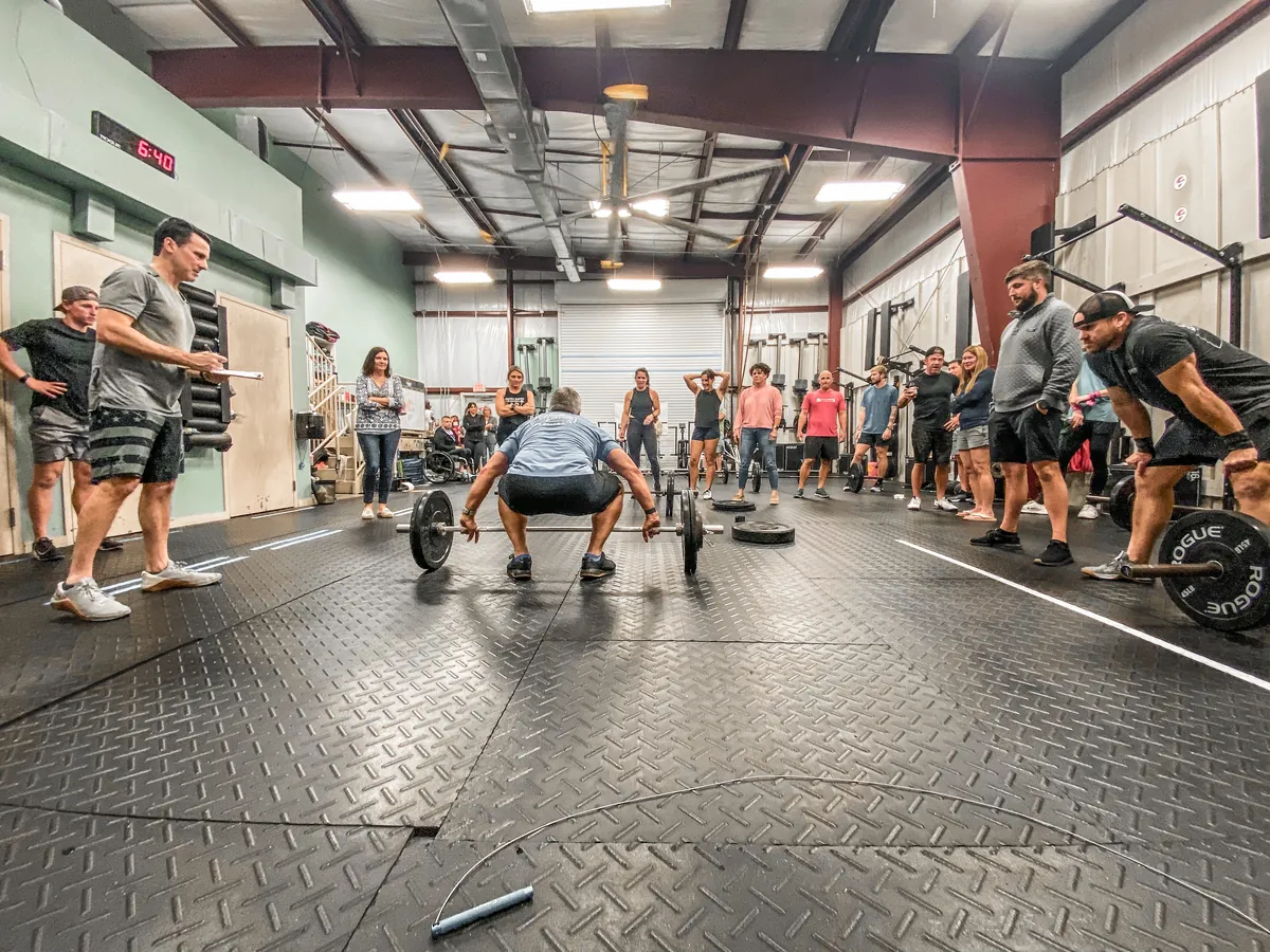 The whole gym gathered around a member setting up a deadlift