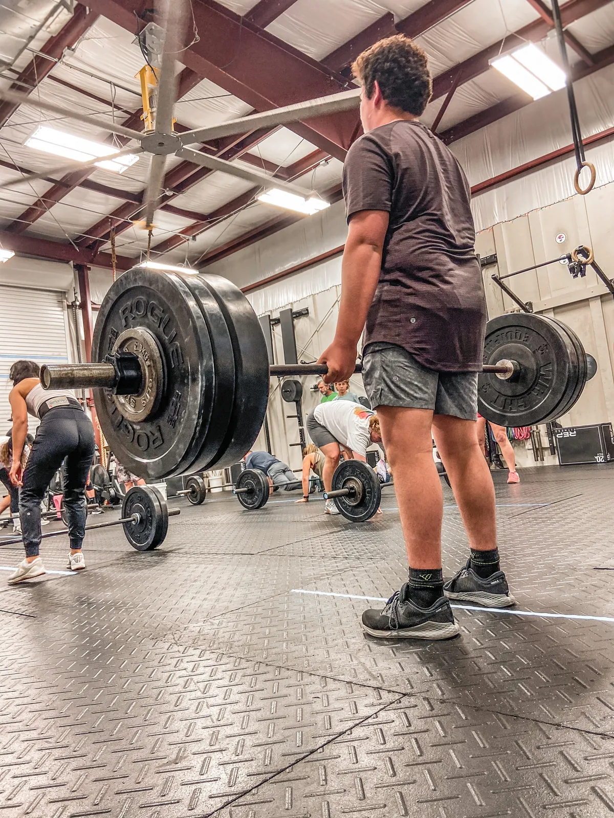 A young member stepping up to a loaded barbell