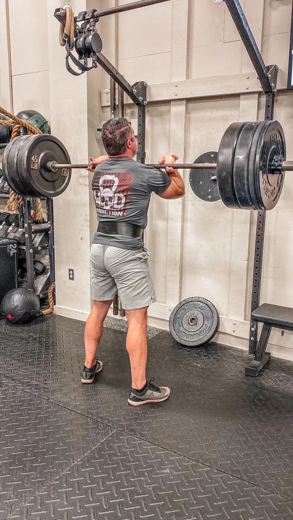 A member pressing a barbell overhead