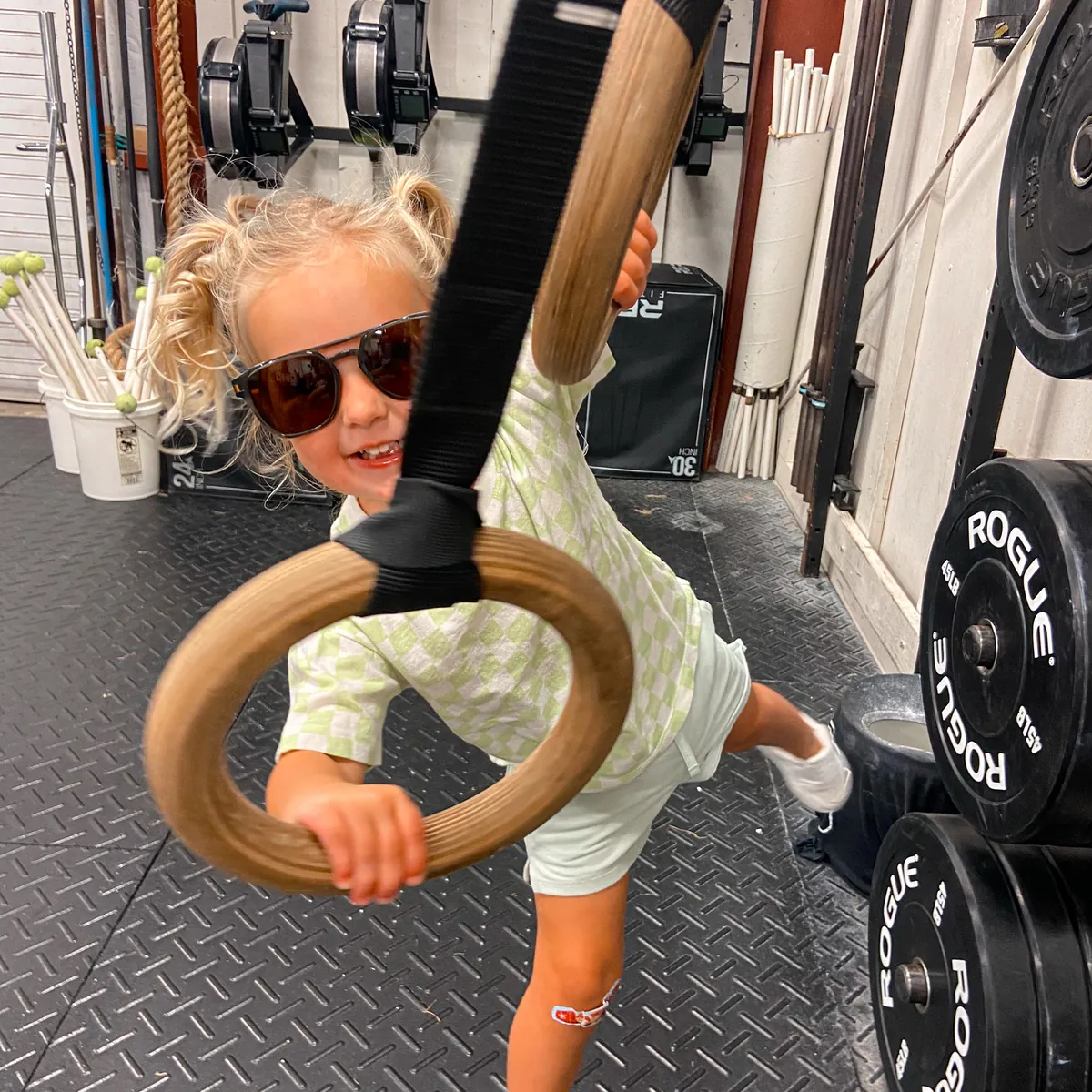 A little one swinging on the rings in sunglasses